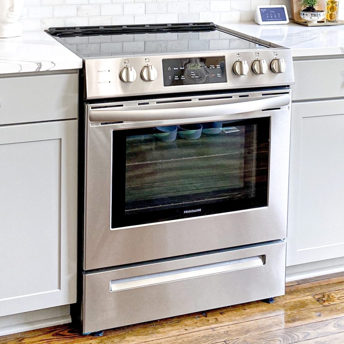 Zilveren oven in een witte keuken. Er zit een lade onder de oven