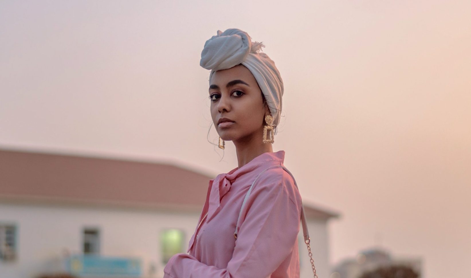 Vrouw met Barbie roze blouse en gouden oorbellen voor een roze achtergrond