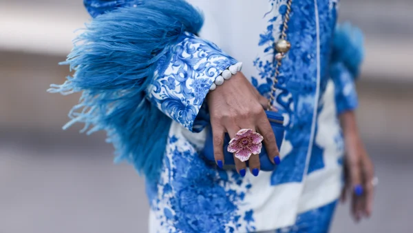 Valentino pak met blauwe tekeningen en veren, een hand met een bloemenring op straat