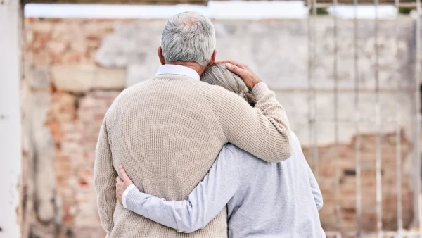 Oude man en oude vrouw van achter, ze omhelzen elkaar. Veteraan en meisje zijn herenigd