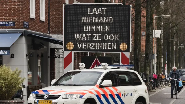 Bord op straat dat waarschuwt voor babbeltrucs met politie-auto ervoor