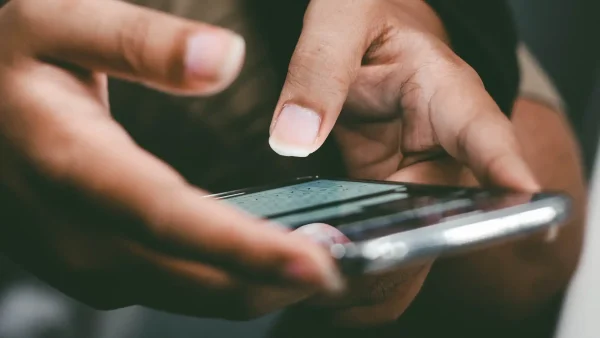 Foto van twee handen die een telefoon vasthouden met een berichten-app geopend