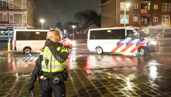 agent staat voor twee politiewagens