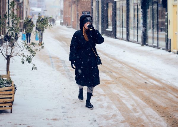 vrouw loopt op straat in sneeuw