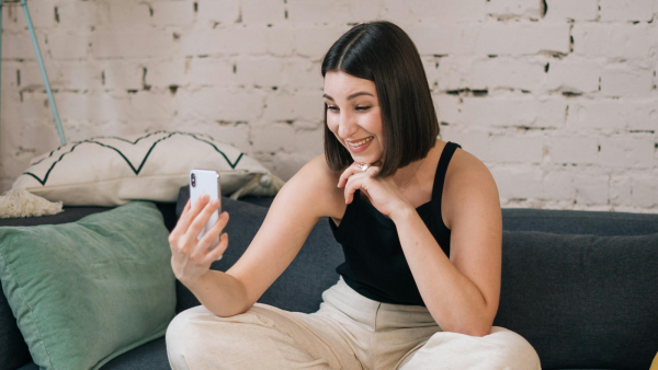 Lachende vrouw op bank met telefoon in hand