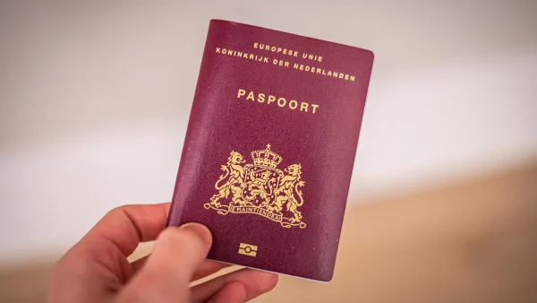 Hand houdt een Nederlands paspoort vast