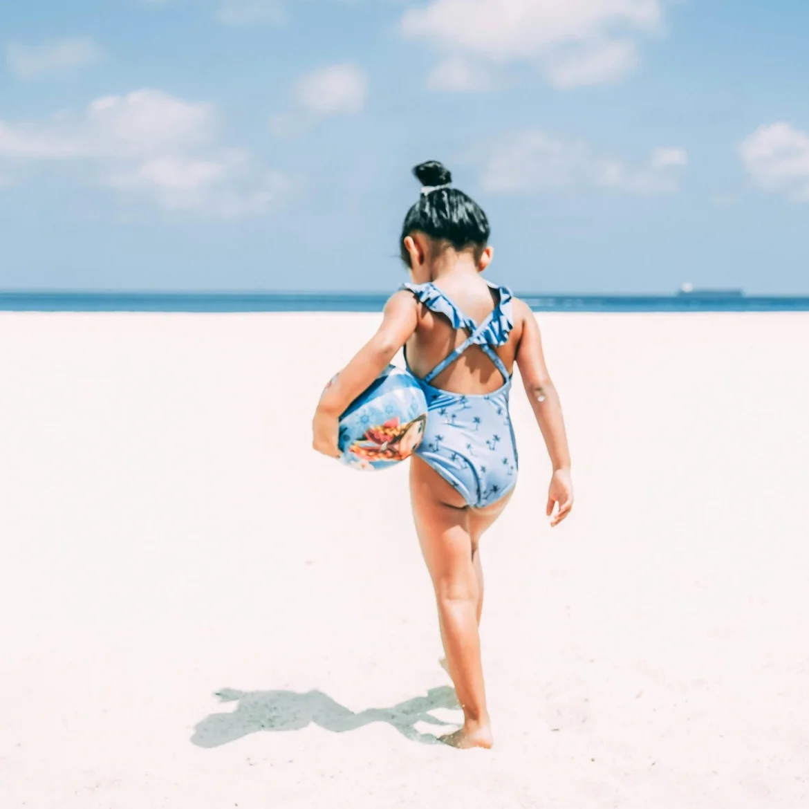 zonnebrand voor kinderen kind dat op het strand loopt met bal