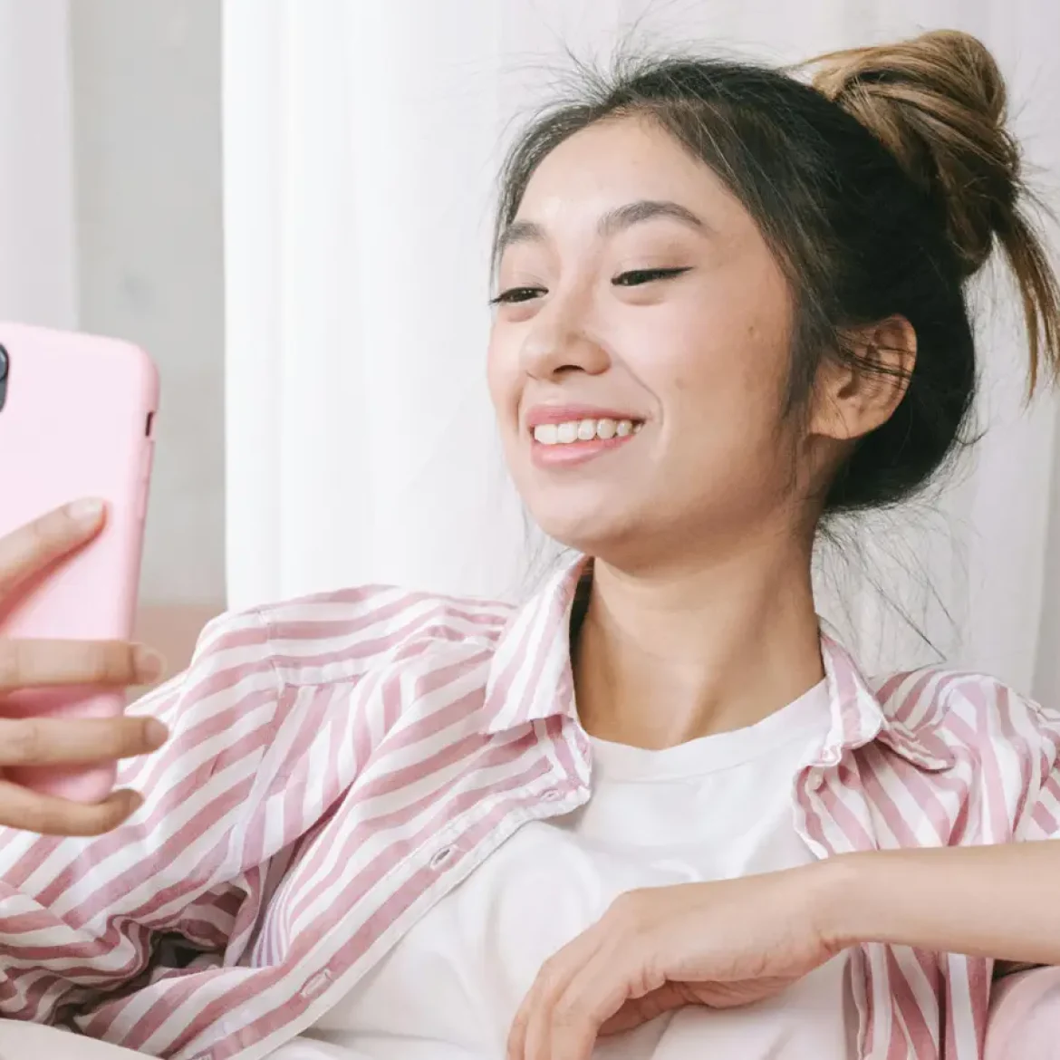 Aziatische vrouw glimlacht naar telefoon