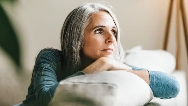 Vrouw kijkt uit het raam en denkt terug aan kindertijd