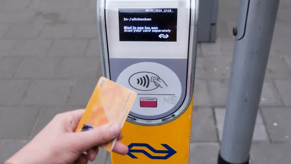 Iemand checkt in met een ov-chipkaart bij een incheckpaal van de NS