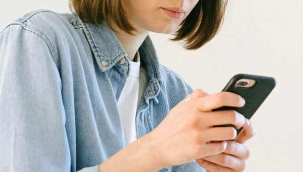 Vrouw kijkt naar mobiel in haar handen