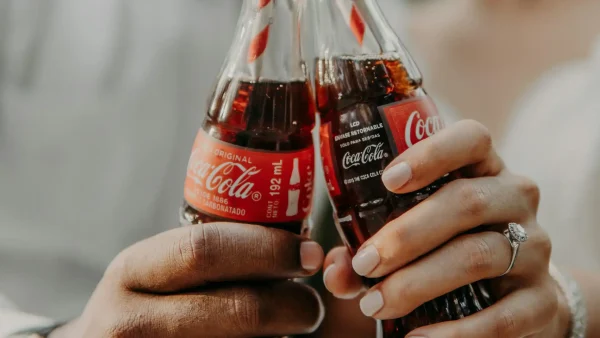 Twee mensen houden een flesje Coca-Cola vast