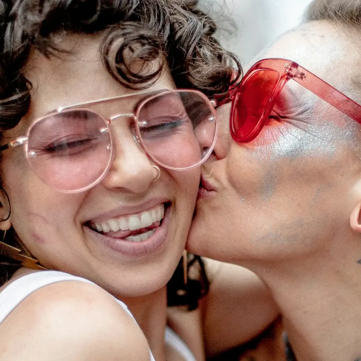 Een vrouw zoent een andere vrouw op de wang tijdens Pride