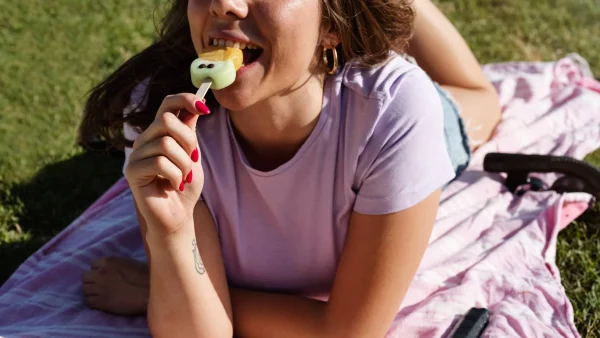 Vrouw eet ijsje in de zon met warm weer