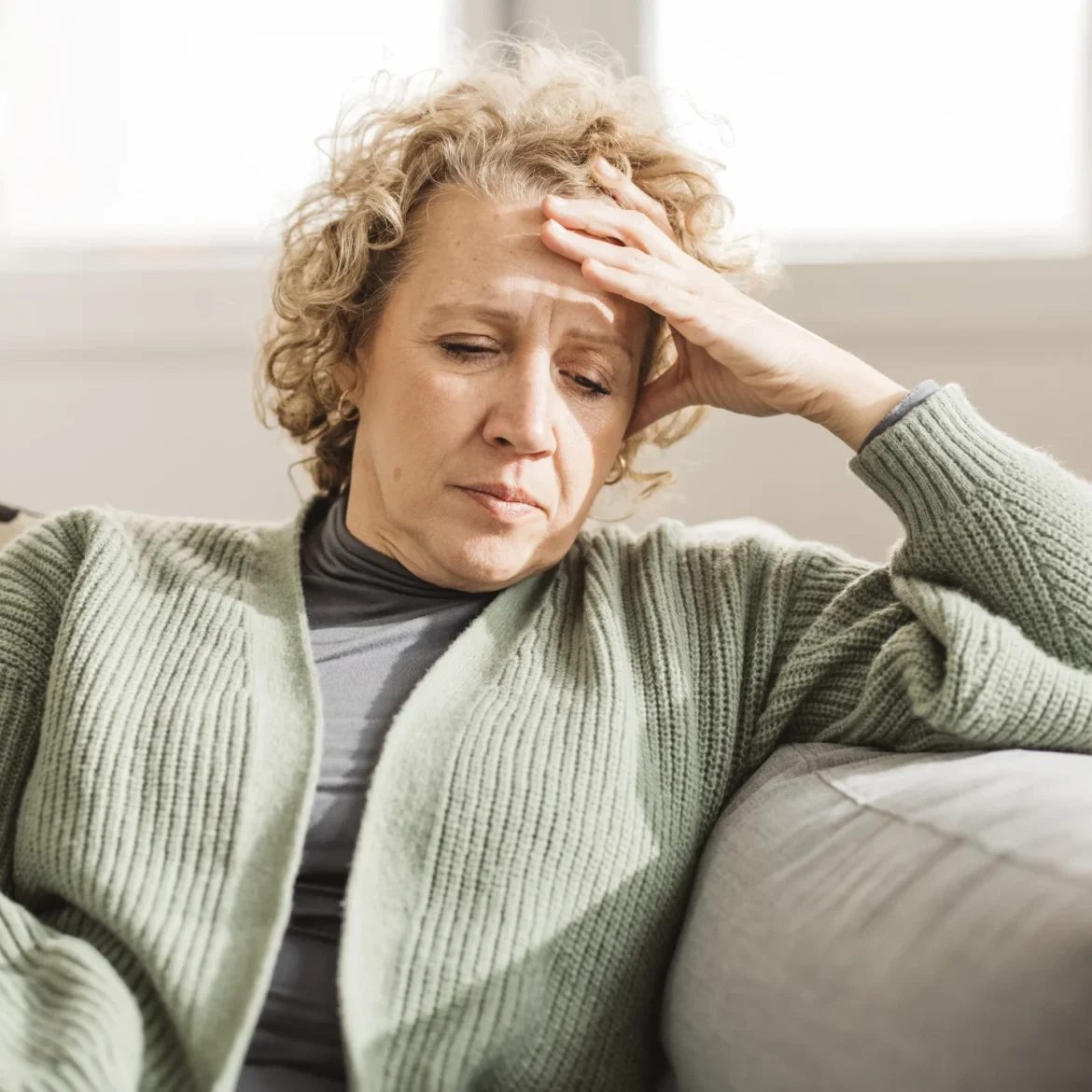 Vrouw julia zit op de bank en steunt op haar hoofd door zorgen om samengesteld gezin