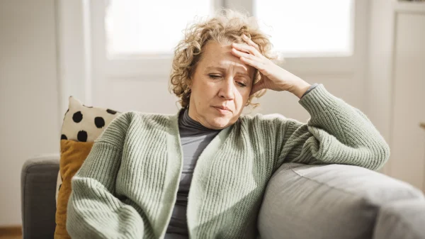 Vrouw julia zit op de bank en steunt op haar hoofd door zorgen om samengesteld gezin