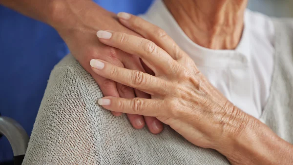 Oudere vrouw met Alzheimer houdt hand verpleegkundige vast.