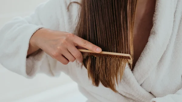 Vrouw kamt haar haren en heeft last van haaruitval