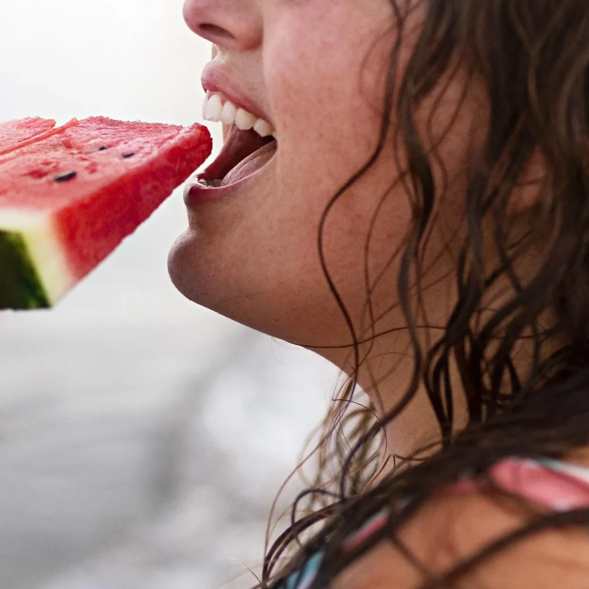 een vrouw eet watermeloen in de zon