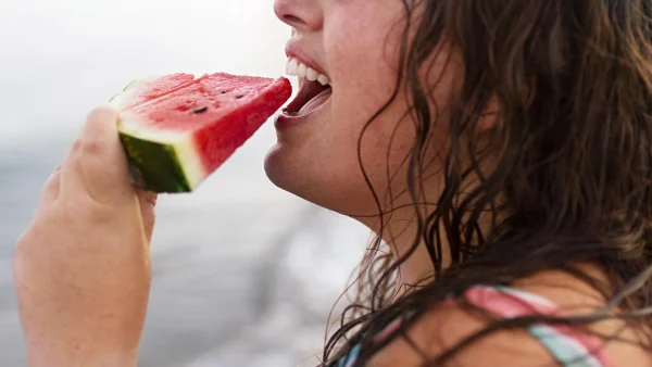 een vrouw eet watermeloen in de zon