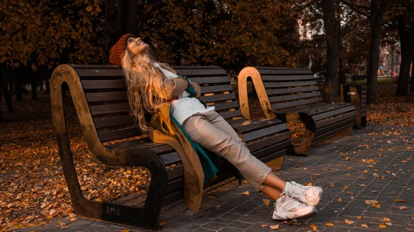 Vrouw in de herfst op bankje met sneakers