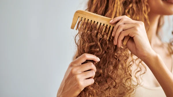 Vrouw met rode krullen kamt haar haren