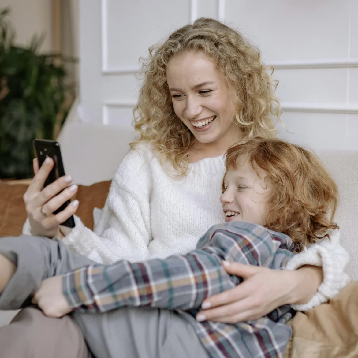 moeder kijkt lachend met haar kind op een mobiele telefoon