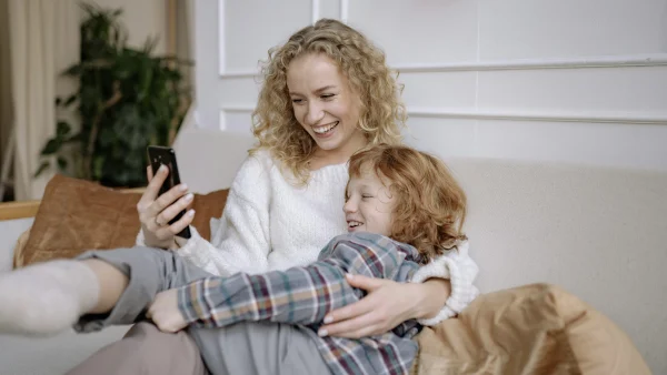 moeder kijkt lachend met haar kind op een mobiele telefoon