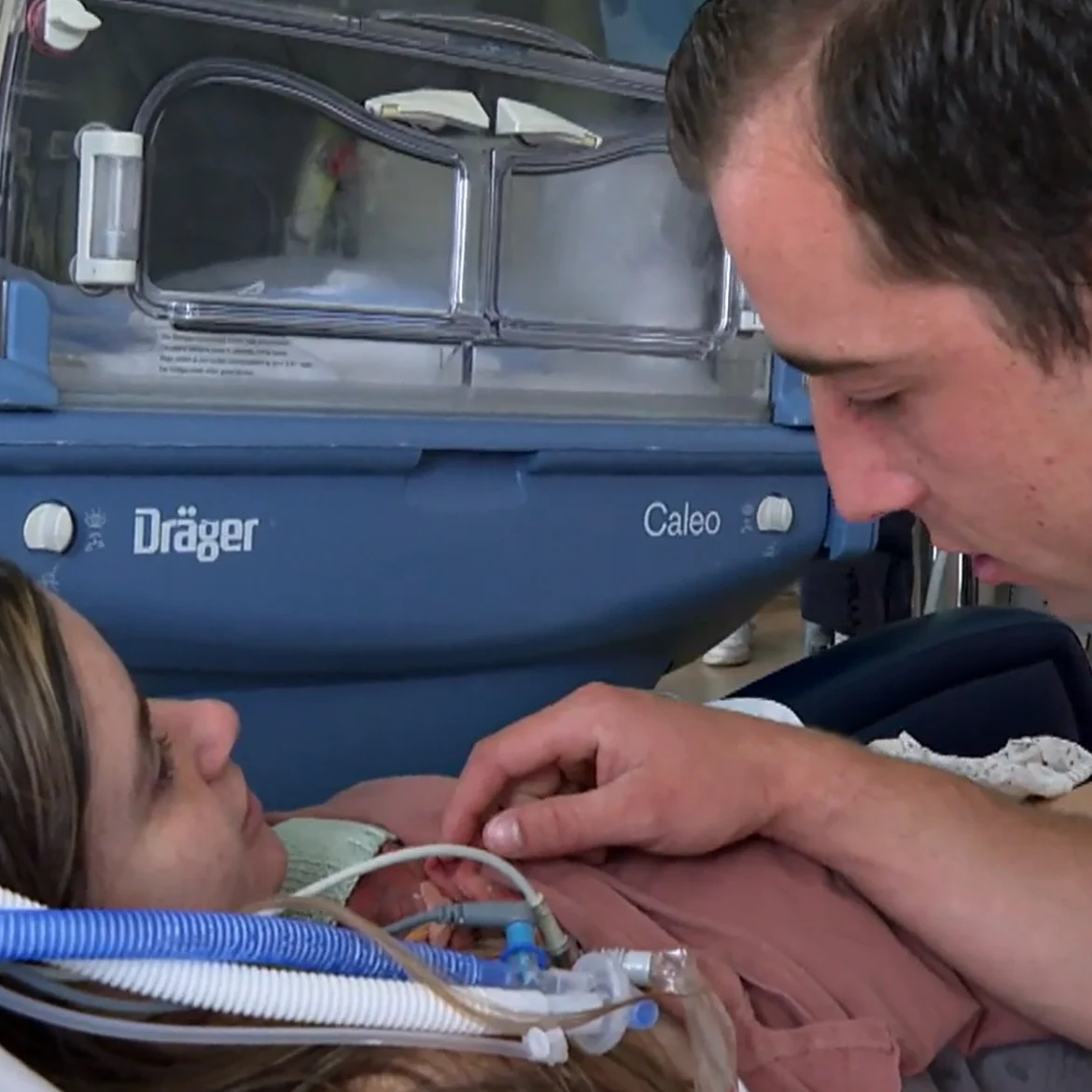 Angela en Damian met baby Cas in Handen aan de Couveuse