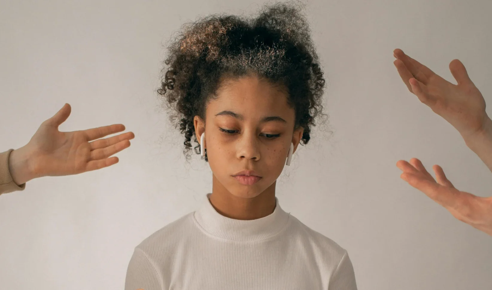 Kind met oortjes in en wijzende handen om haar heen