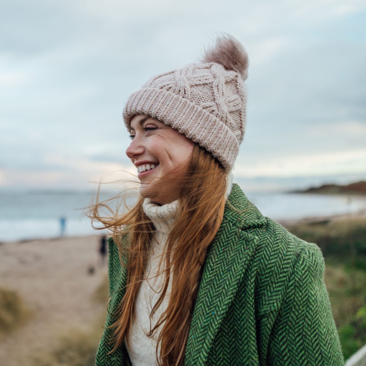 vrouw op strand met muts winter