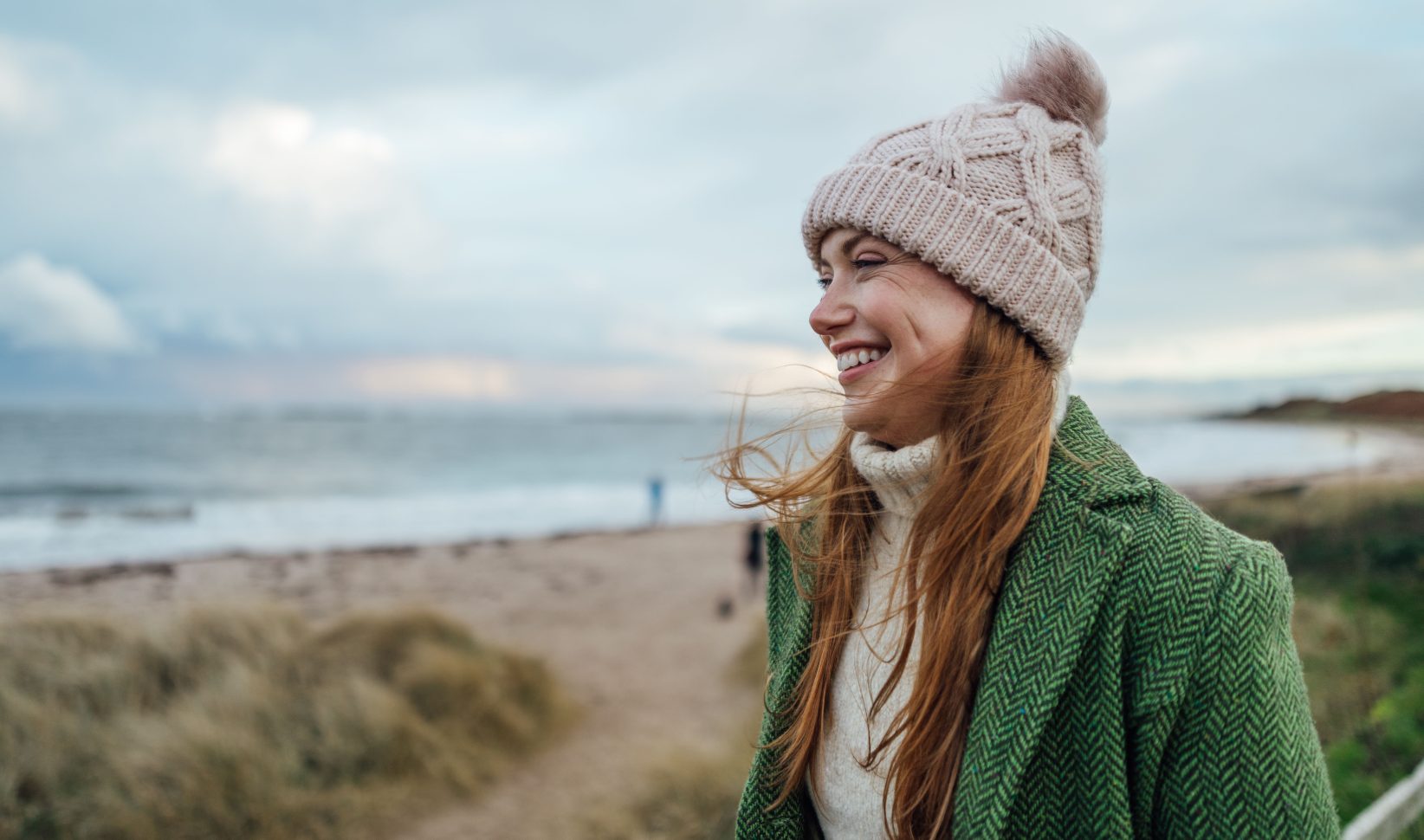 vrouw op strand met muts winter