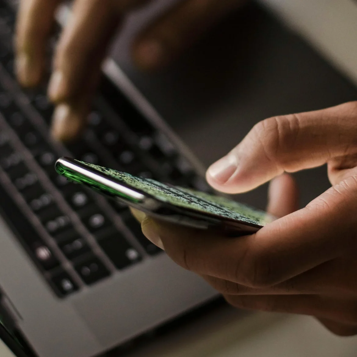 man met laptop en smartphone | Nederlander opgepakt voor verkoop intieme beelden op Telegram