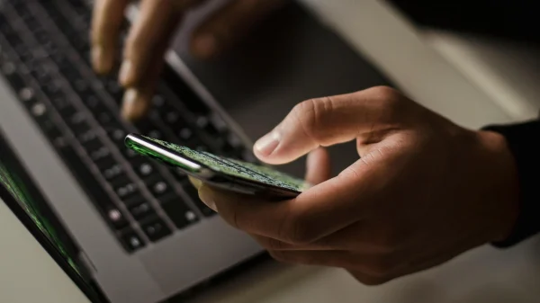 man met laptop en smartphone | Nederlander opgepakt voor verkoop intieme beelden op Telegram